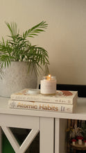 Load image into Gallery viewer, Lit candle staged atop stacked books