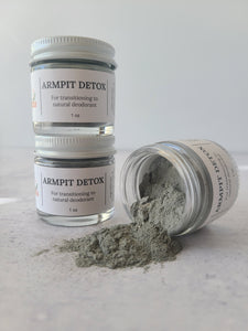 2 one ounce jars of armpit detox stacked next to 1 jar open and on its side with the powder spilling out