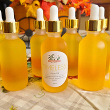 Load image into Gallery viewer, multiple golden anti-aging face oil 2 oz bottles in front of fall décor 
